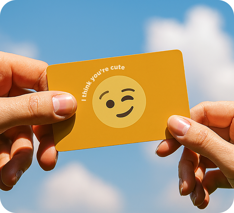 Two hands holding a card that says 'I think you're cute' against blue sky